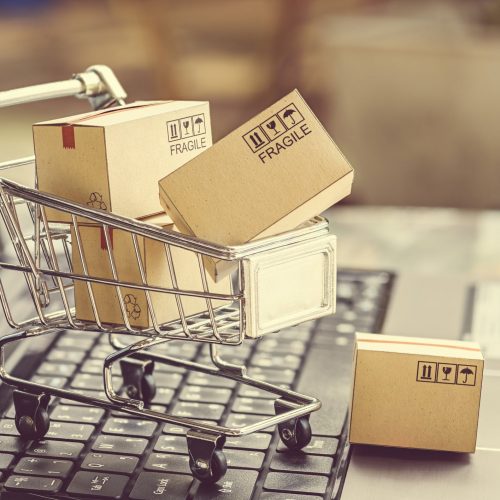 Paper boxes in a shopping cart on a laptop keyboard. Ideas about e-commerce, e-commerce or electronic commerce is a transaction of buying or selling goods or services online over the internet.